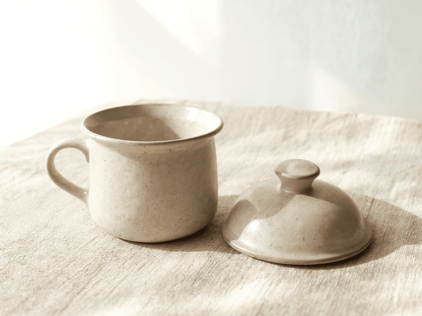 Stoneware butter crock with its lid resting beside it
