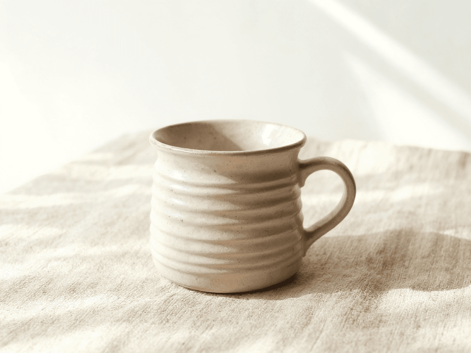 Handmade stoneware mug with throwing ridges and thumb-rest handle